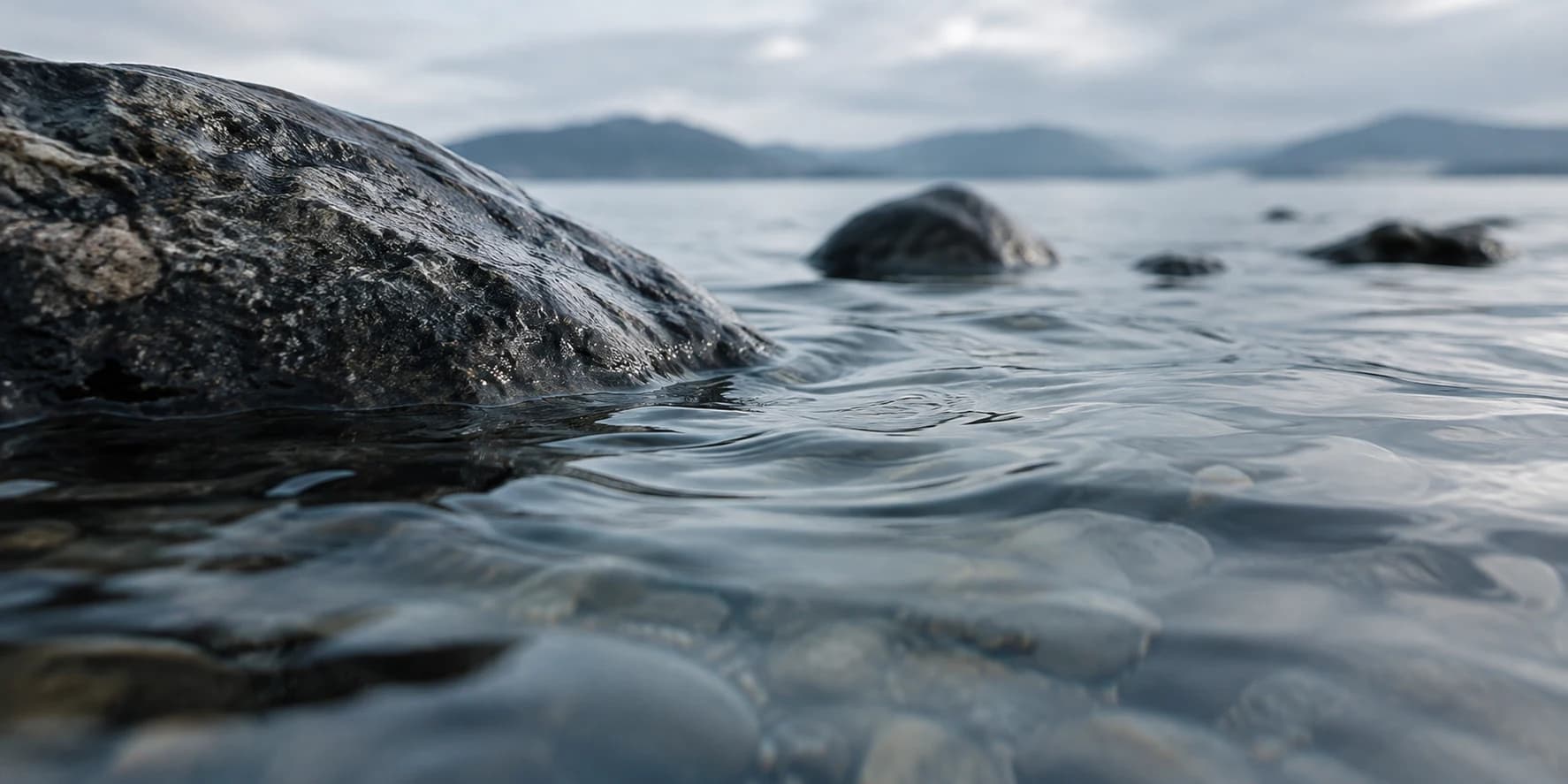 Soft ripples moving around weathered stones in shallow water. Original AI-generated image.